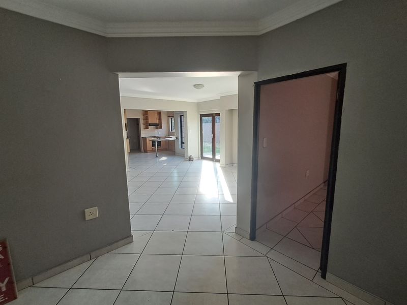 An open-plan living and kitchen area featuring neutral tiled flooring, built-in cabinetry, and direct access to the outdoor space through sliding glass doors.