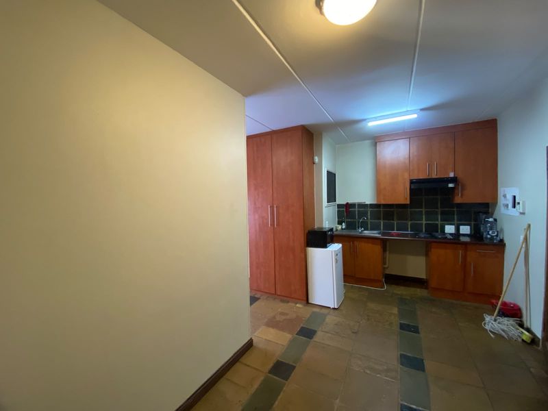 A functional kitchen featuring wooden cabinetry, stone tile flooring, and a tiled backsplash, offering a practical layout for daily use.