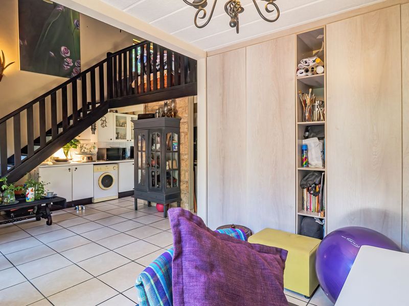 Open plan living area featuring a staircase, extensive built-in cabinetry with integrated shelving, and tiled flooring throughout.