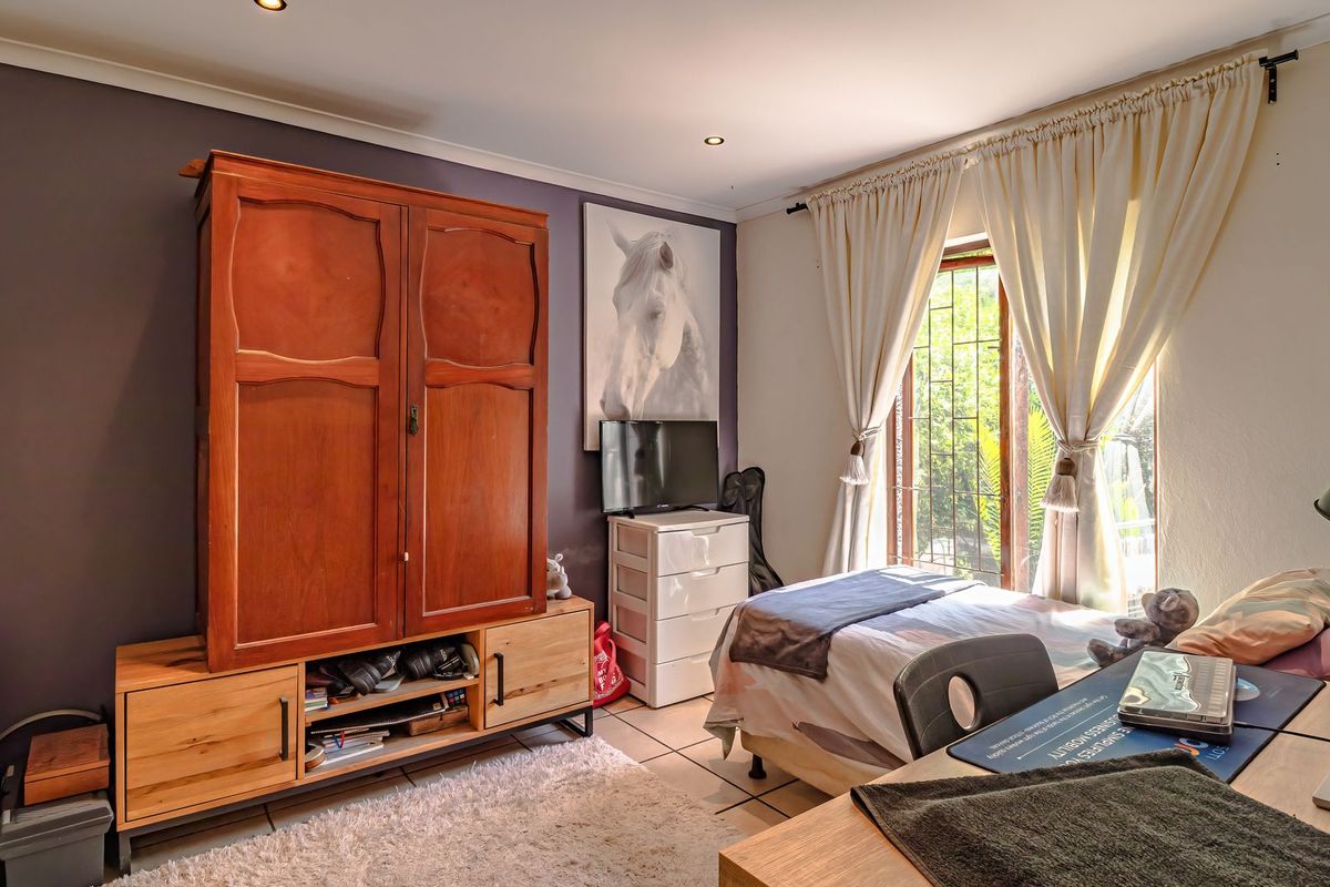 A bedroom featuring tiled flooring, recessed downlighting, and large windows with curtain rails, offering a functional space with potential for modern updates.