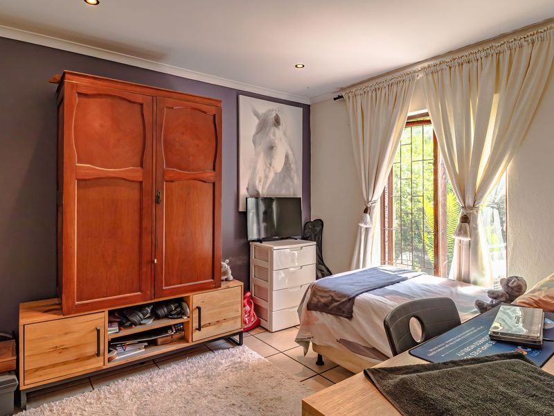 A bedroom featuring tiled flooring, recessed downlighting, and large windows with curtain rails, offering a functional space with potential for modern updates.