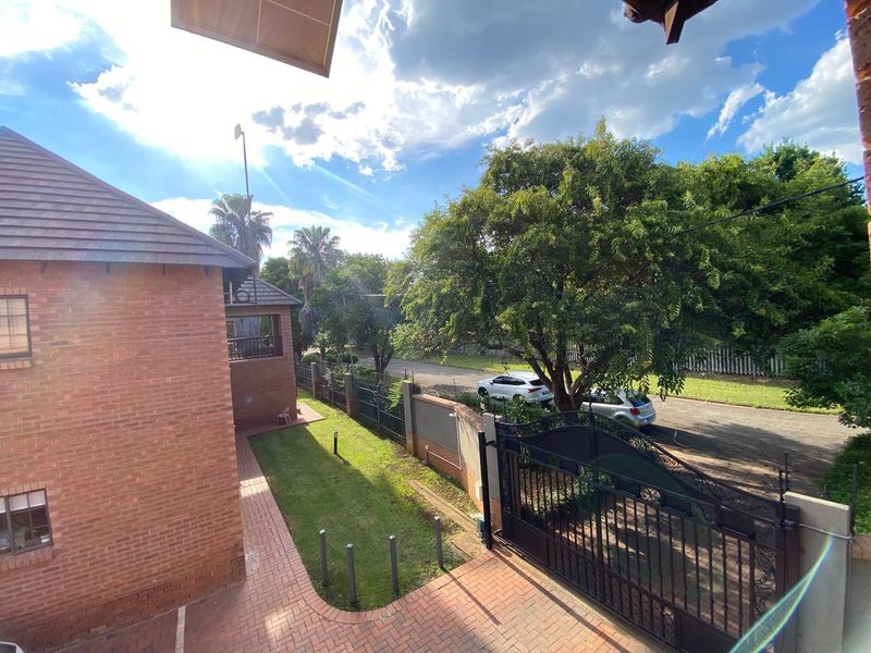 An elevated view of the apartment complex exterior, featuring a brick facade, paved driveway, and secure wrought iron gated entrance.