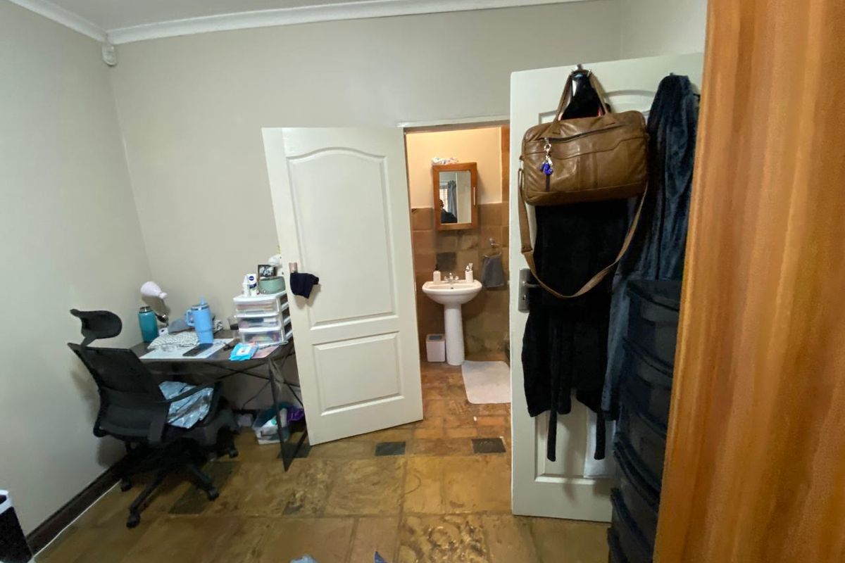 A bedroom featuring tiled flooring and direct access to an en-suite bathroom with a pedestal sink.