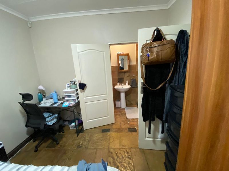 A bedroom featuring tiled flooring and direct access to an en-suite bathroom with a pedestal sink.
