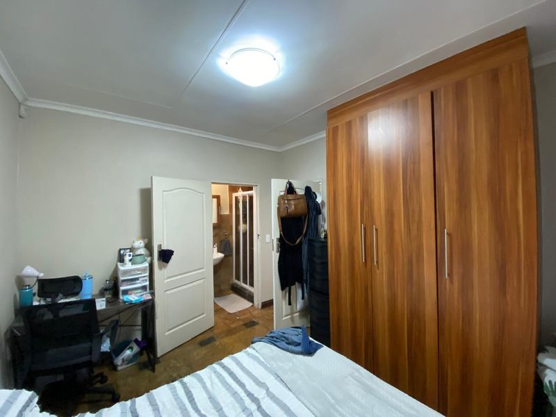 A bedroom featuring a large built-in wooden wardrobe and direct access to an en-suite bathroom.