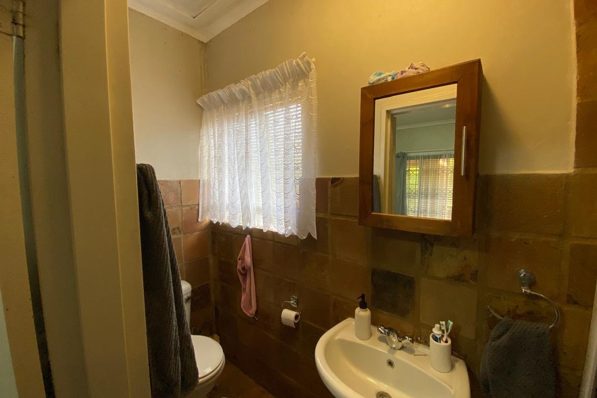 A compact bathroom featuring a wall-mounted basin, medicine cabinet, and ceramic wall tiling. The space would benefit from modern updates to finishes and fixtures.