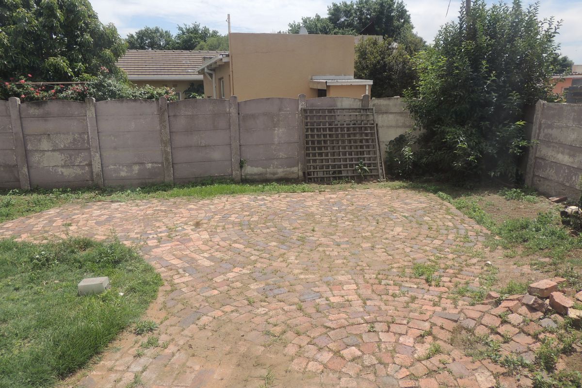 Rear garden area featuring a cobblestone paved patio enclosed by a precast concrete boundary wall.
