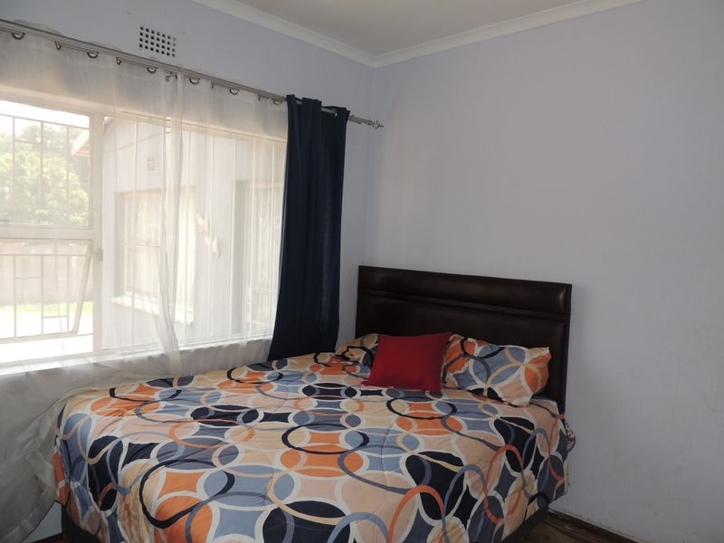 A standard bedroom featuring a window with curtain rod and simple cornice detailing.