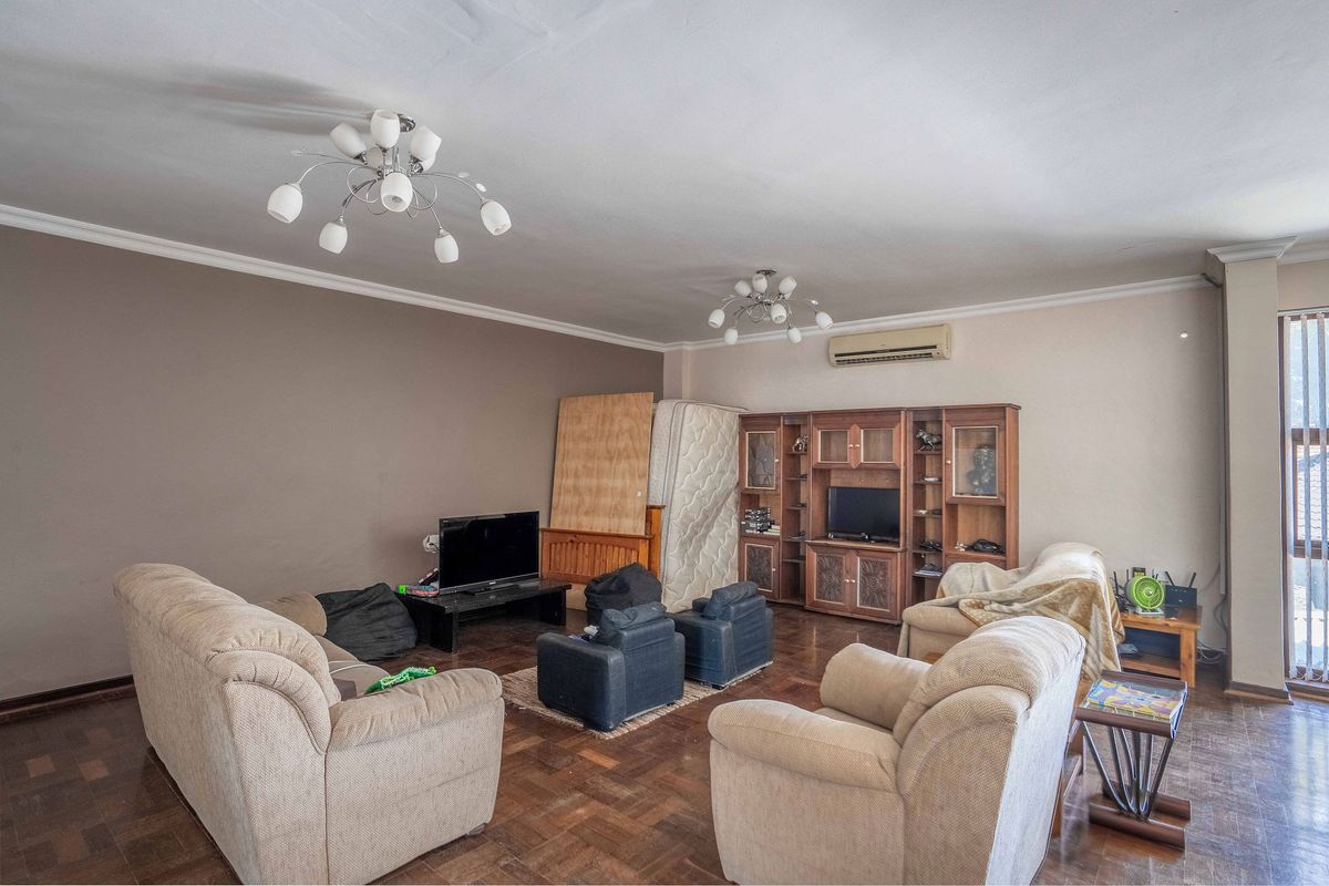 Spacious living room featuring classic parquet flooring, built-in display cabinetry, and a wall-mounted air conditioning unit.
