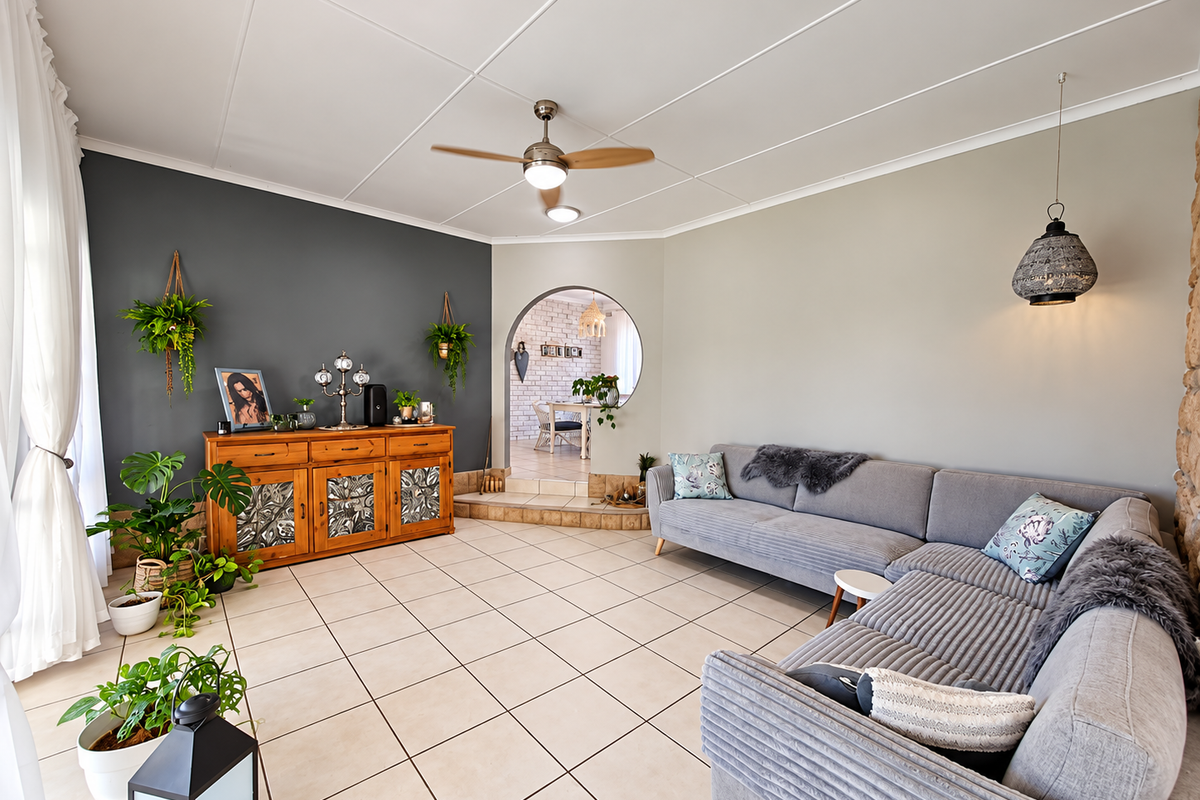 Spacious living room featuring tiled flooring, a ceiling fan, and a distinctive arched opening leading to the adjacent dining area.