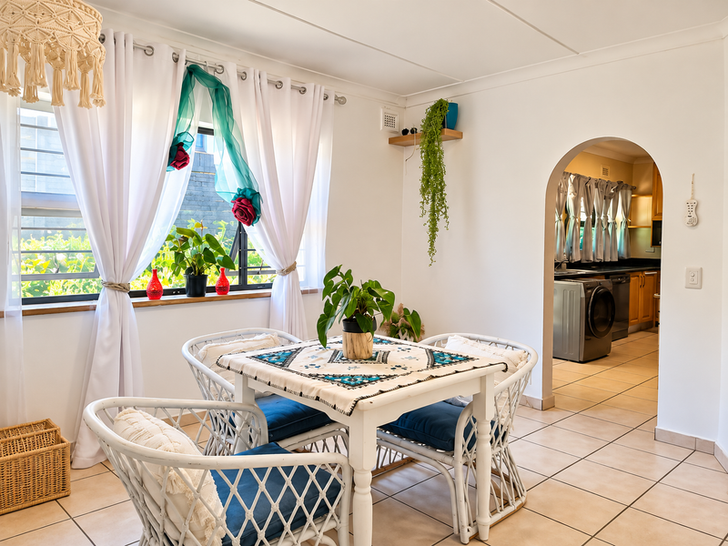 A bright dining area featuring tiled flooring and a classic archway leading into the kitchen, creating a seamless flow between living spaces.
