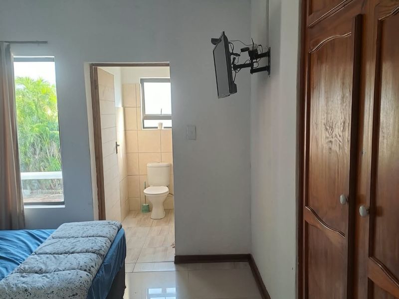 Bedroom featuring tiled flooring, a built-in wooden wardrobe, ceiling fan, and direct access to an en-suite bathroom.