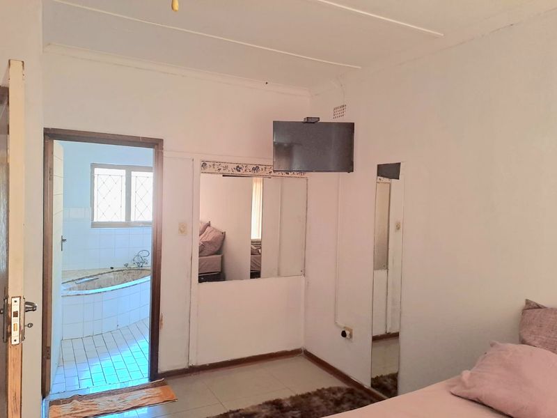Bedroom featuring tiled flooring and direct access to an en-suite bathroom, with built-in mirror and wall-mounted television.