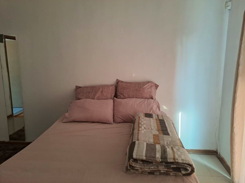 A simple bedroom featuring neutral walls and tiled flooring, providing a functional and basic sleeping space.