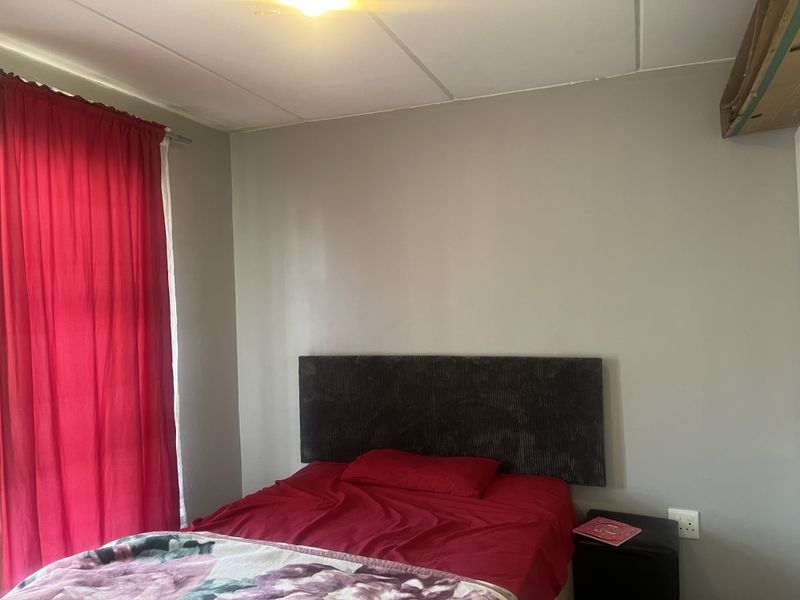 A bedroom featuring neutral wall tones and standard ceiling tiles, offering a functional space ready for personalization and cosmetic updates.