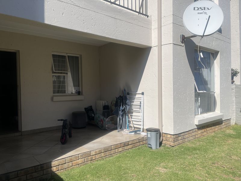 A covered ground-floor patio area featuring tiled flooring, brick detailing, and direct access to the garden space.