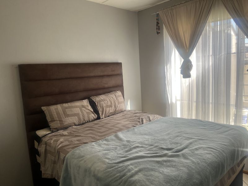 A bedroom featuring neutral wall finishes and a window with installed curtain rails, providing natural light to the space.