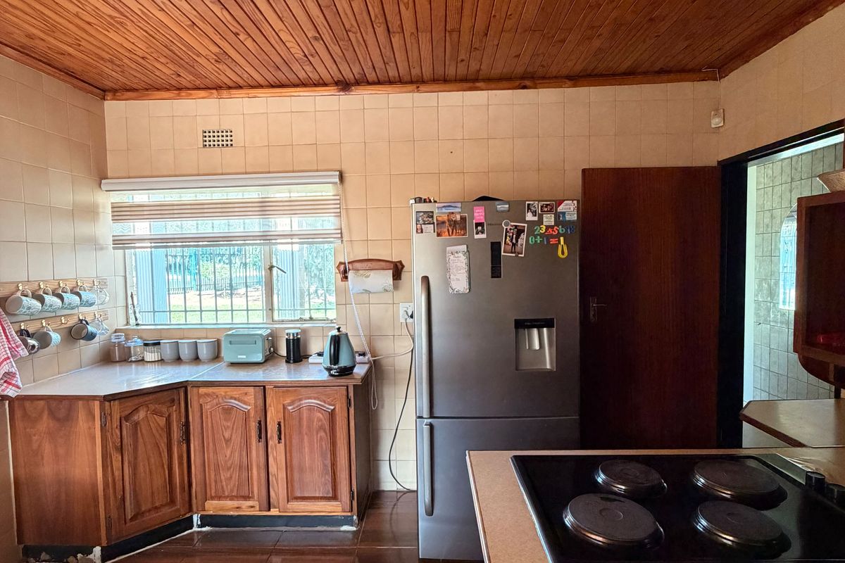 A functional kitchen featuring wooden cabinetry, tiled backsplash, and a distinctive wooden ceiling, offering a traditional aesthetic with potential for modern updates.