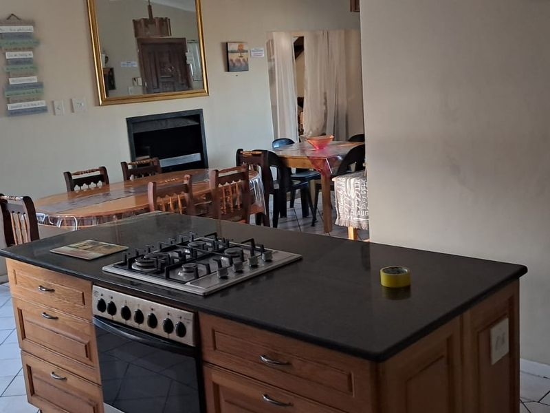 Open plan living area featuring a kitchen island with gas hob and oven, tiled flooring, and a fireplace, flowing into the dining space.