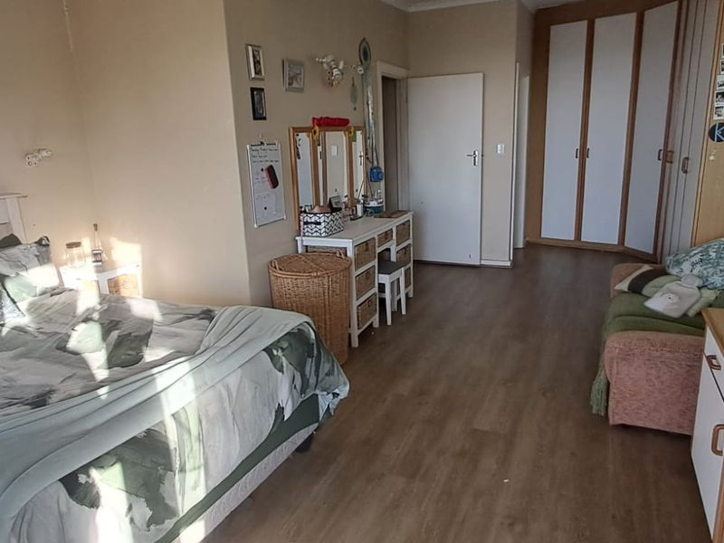 Spacious bedroom featuring laminate flooring and built-in cupboards, offering a comfortable layout with ample natural light.