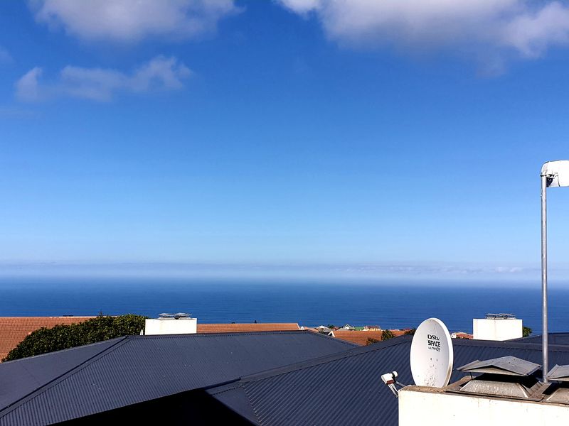 A clear elevated view overlooking the ocean and surrounding residential rooftops, featuring a satellite dish and antenna installation.