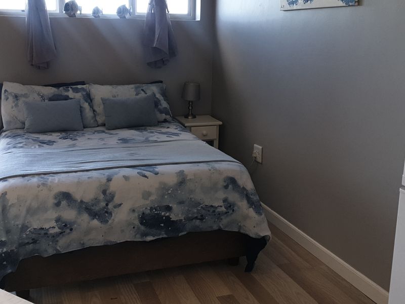 A compact bedroom featuring laminate flooring and a horizontal window, providing a functional sleeping space within the apartment.