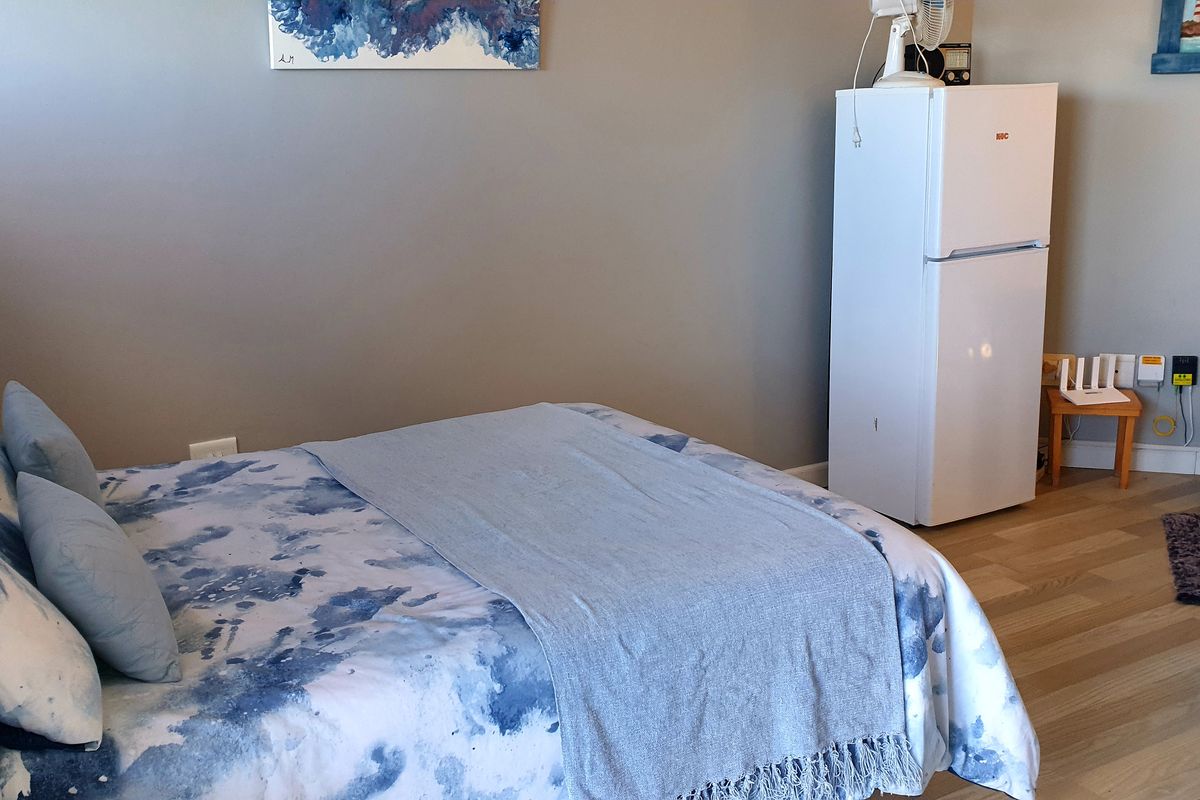 A bedroom featuring light-toned laminate flooring and neutral wall finishes, providing a functional space for rest.