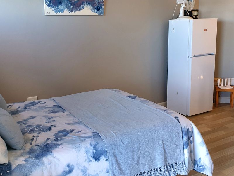 A bedroom featuring light-toned laminate flooring and neutral wall finishes, providing a functional space for rest.