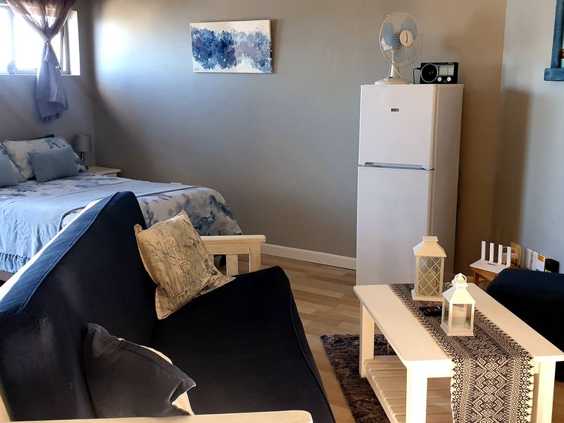 An open-plan studio apartment featuring laminate flooring and a combined living and sleeping area with neutral wall finishes.