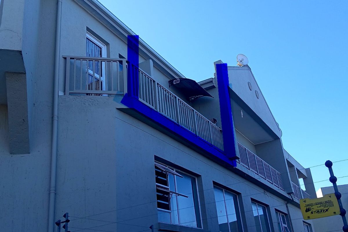 Exterior view of an apartment building featuring a balcony with a damaged balustrade section and installed electric fencing.