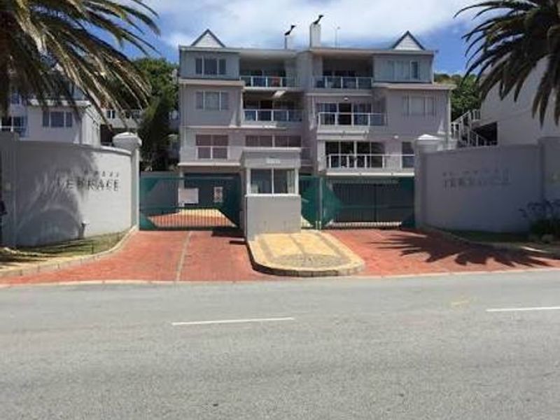 Front exterior view of the apartment complex featuring a secure gated entrance, guard house, and multi-level balconies.