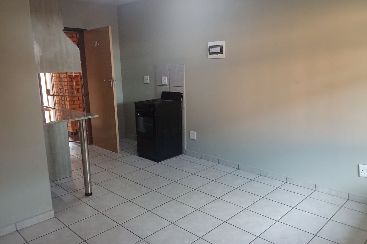 A functional kitchen area featuring tiled flooring, a breakfast bar, and a freestanding stove, offering a clean and simple layout.