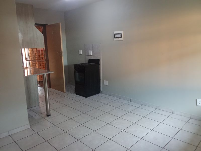 A functional kitchen area featuring tiled flooring, a breakfast bar, and a freestanding stove, offering a clean and simple layout.