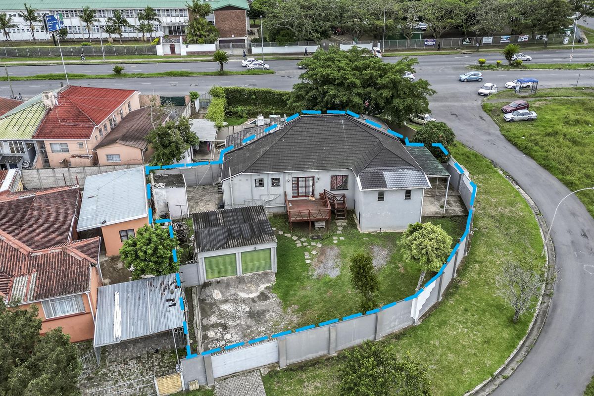 Aerial view of a residential property featuring a tiled roof house, double garage, wooden deck, and enclosed garden area with perimeter walling.