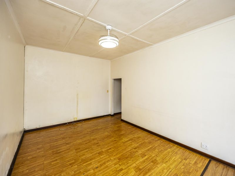 An empty bedroom featuring laminate flooring, a ceiling fan, and neutral walls, offering a blank canvas for personalization.