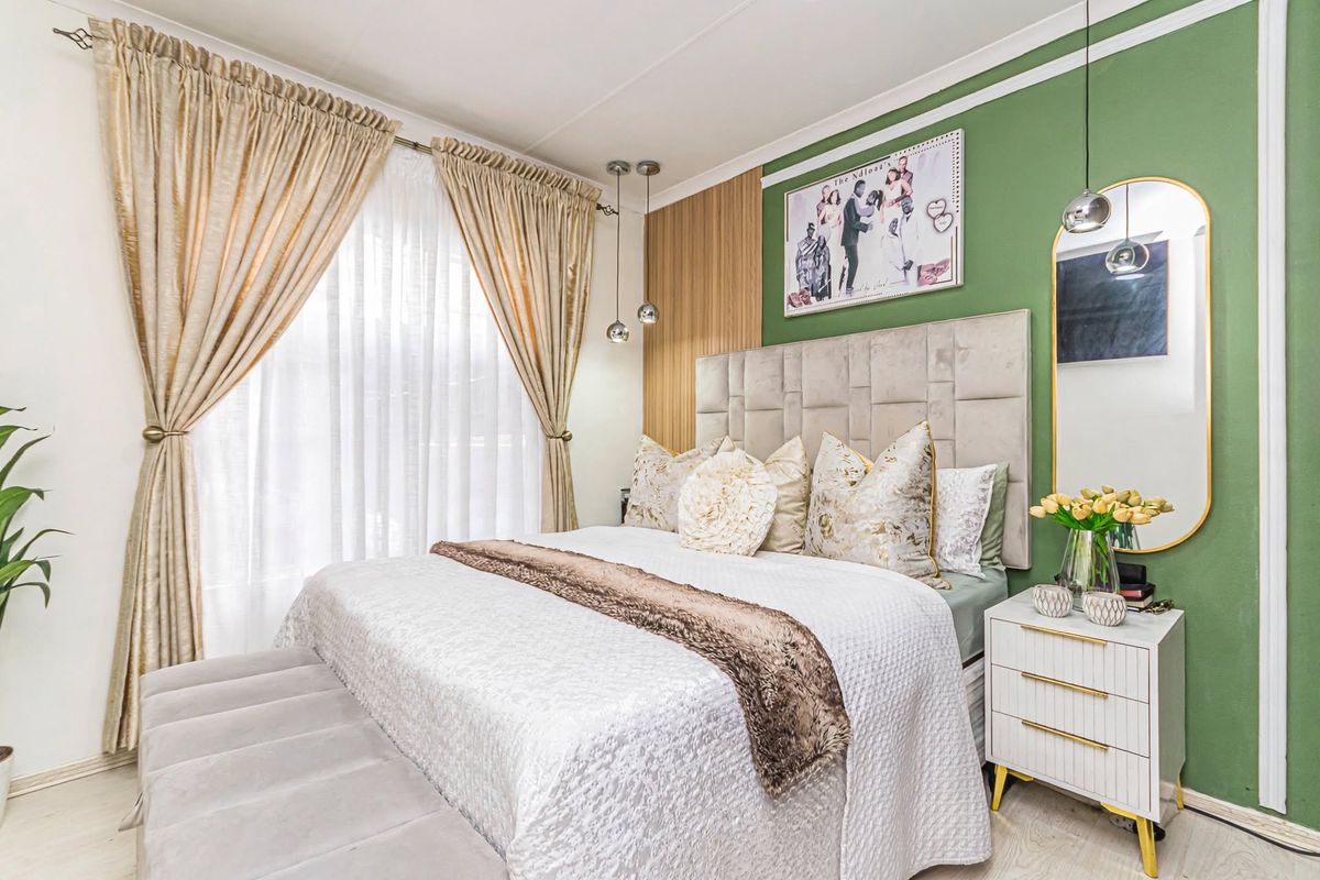 A well-maintained bedroom featuring an accent wall, modern pendant lighting, and light-toned laminate flooring, creating a bright and inviting atmosphere.