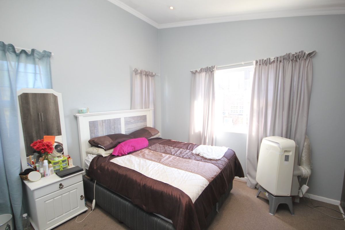 A well-proportioned bedroom featuring neutral wall tones, carpeted flooring, and recessed ceiling lighting, offering a comfortable and functional living space.