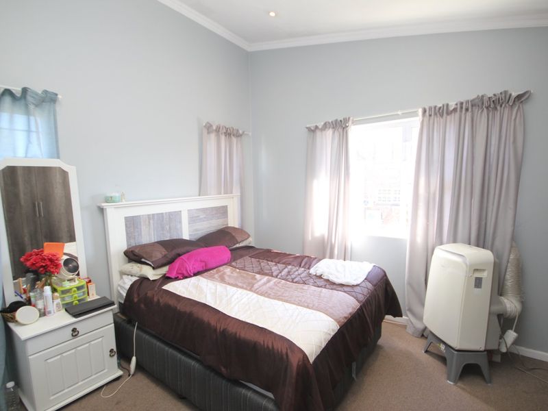 A well-proportioned bedroom featuring neutral wall tones, carpeted flooring, and recessed ceiling lighting, offering a comfortable and functional living space.