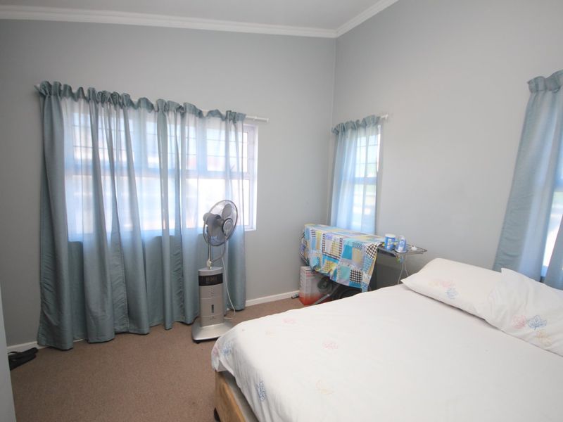 A standard bedroom featuring neutral wall paint, carpeted flooring, and multiple windows with curtain fixtures.