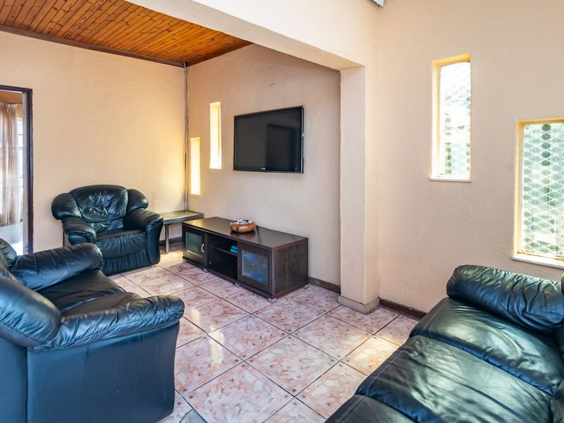 A living room featuring a timber ceiling, tiled flooring, and built-in wall niches, offering a dated aesthetic ready for modernization.