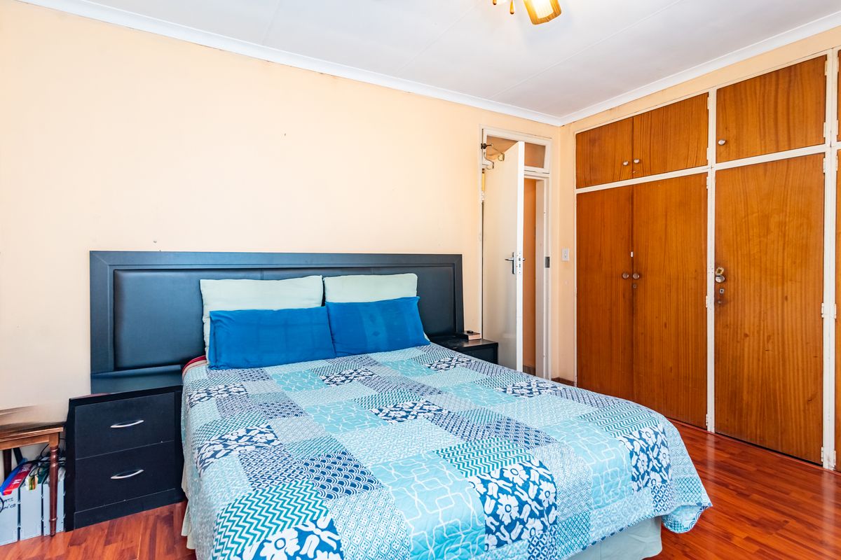 A bedroom featuring laminate flooring and built-in wooden cupboards, offering functional storage space.