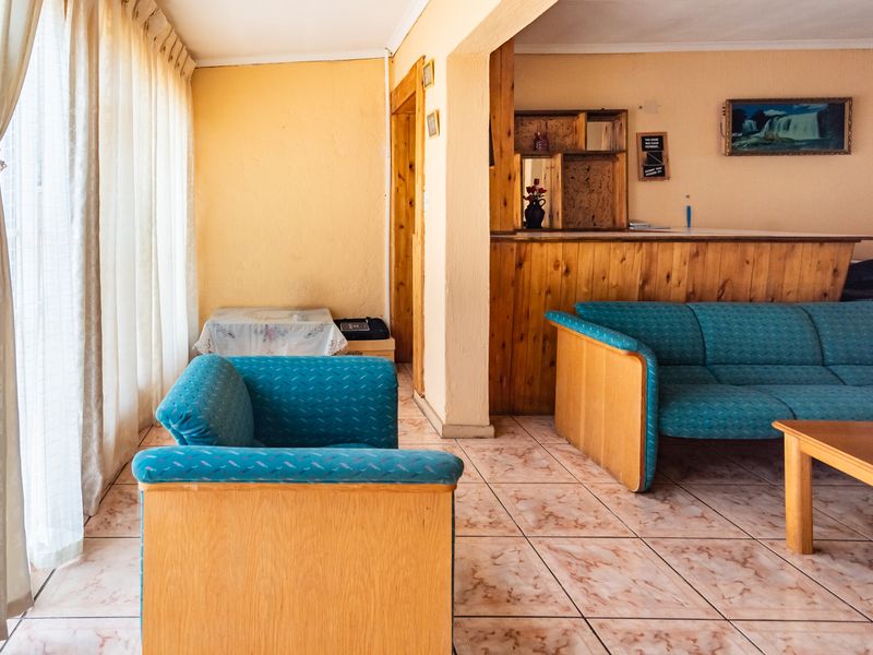 Living room featuring tiled flooring and a built-in wooden bar counter, offering a dated aesthetic with potential for modern renovation.