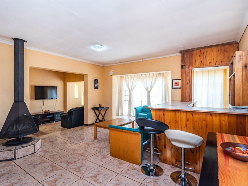 Open plan living and kitchen area featuring a prominent freestanding fireplace, tiled flooring, and a timber breakfast bar with integrated cabinetry.