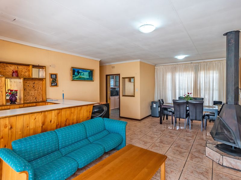 Open plan living and dining area featuring a built-in wooden bar, tiled flooring, and a prominent freestanding metal fireplace.