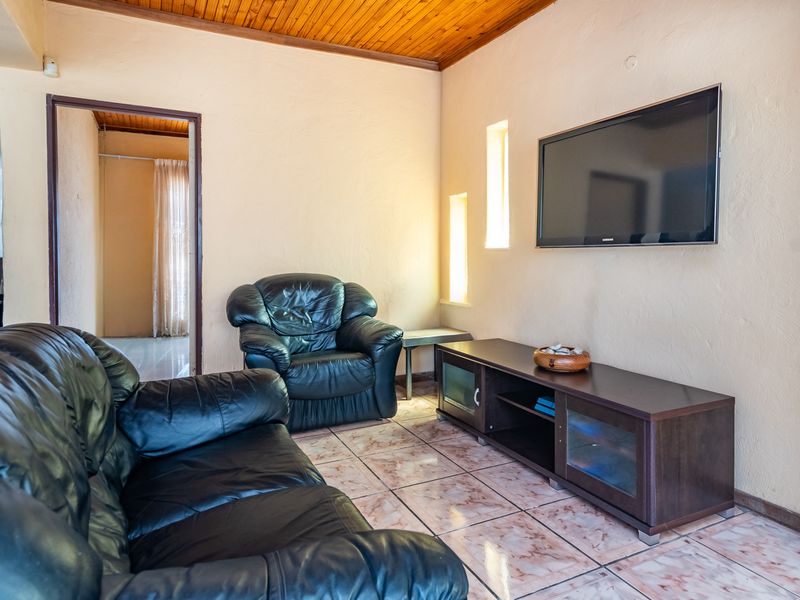 A living room featuring a timber-clad ceiling, tiled flooring, and built-in wall niches, providing a functional space with potential for cosmetic updates.
