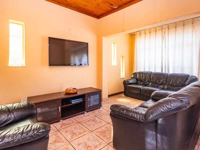 A living room featuring tiled flooring and a timber ceiling, with vertical windows providing natural light.