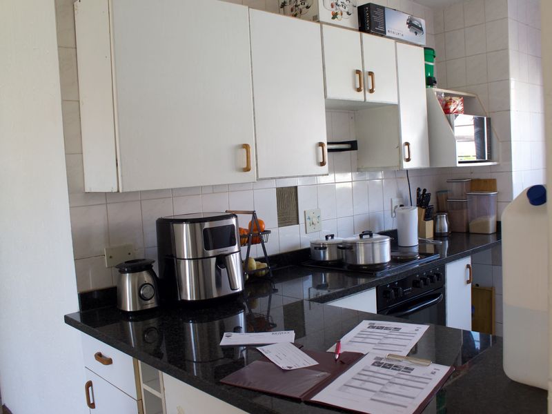 A functional kitchen featuring dark granite countertops, white cabinetry, and a tiled backsplash, offering a practical layout for daily meal preparation.