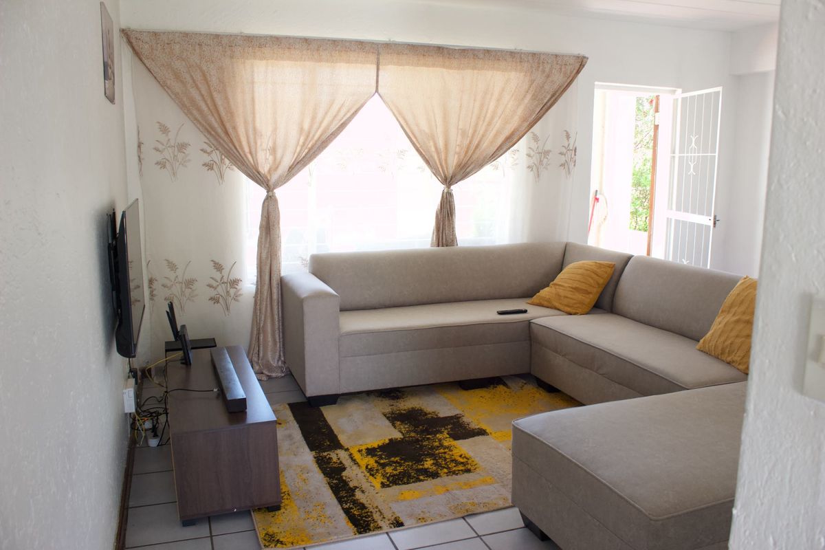 A comfortable living room featuring tiled flooring and direct access to the exterior through a security gate.