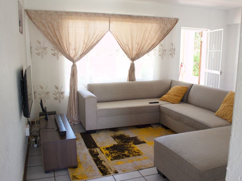 A comfortable living room featuring tiled flooring and direct access to the exterior through a security gate.