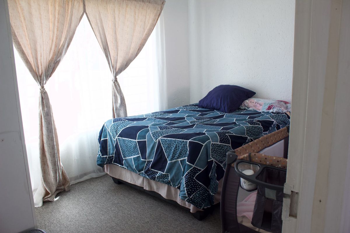 A standard bedroom featuring carpeted flooring and textured walls, providing a functional space with natural light from the window.